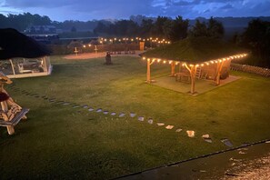 A well-lit outdoor area with a grassy lawn, a wooden structure with string lights, and a pathway leading to a seating area. - Comfortable apartment, 2 levels, close to beach (Ustronie Morskie)