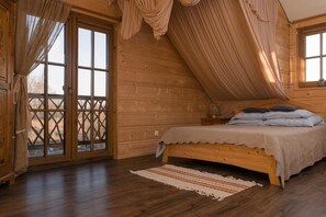 A bedroom with a wooden bed, a window with curtains, and a view of the outdoors. - Comfortable apartment very close to the beach (Ustronie Morskie)