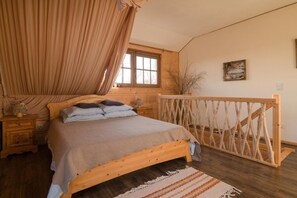 Ein Schlafzimmer mit einem hölzernen Bett, einem Fenster, einem Holzschrank und einem Holzbalken.