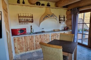 Cuina rústica amb armaris de fusta, un microones vermell i una zona de menjador amb cadires de vimet.