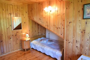 A wooden-paneled room with a bed, a nightstand, and a wall-mounted light fixture. - Large holiday home with private garden (Kopalino)