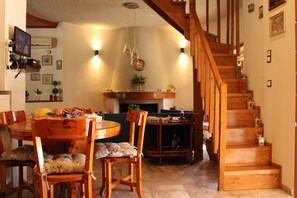 A dining area with a wooden table and chairs, a staircase, and a fireplace.