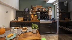 A modern kitchen with a brick backsplash, wooden shelves, and a dining area with a table set for two. - Roncaglia, 27 - Comfort & Character (Milano)