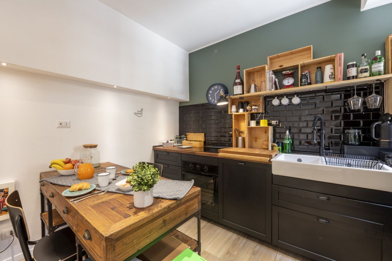 A modern kitchen with a wooden table, a black brick backsplash, and a built-in oven.