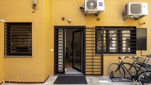A yellow building with a black gate, air conditioning units, and bicycles parked outside. - Roncaglia, 27 - Comfort & Character (Milano)