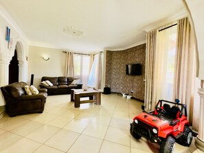 Ein Wohnzimmer mit einer Couch, einem Couchtisch, einem an der Wand befestigten Fernseher und einem roten Spielzeugauto.