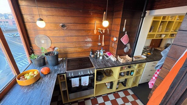 Una cocina con paredes de madera, una estufa, un lavabo y diversos utensilios de cocina.