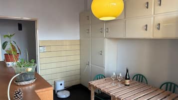 Une cuisine avec une table à manger, des chaises, un luminaire jaune suspendu et des placards.