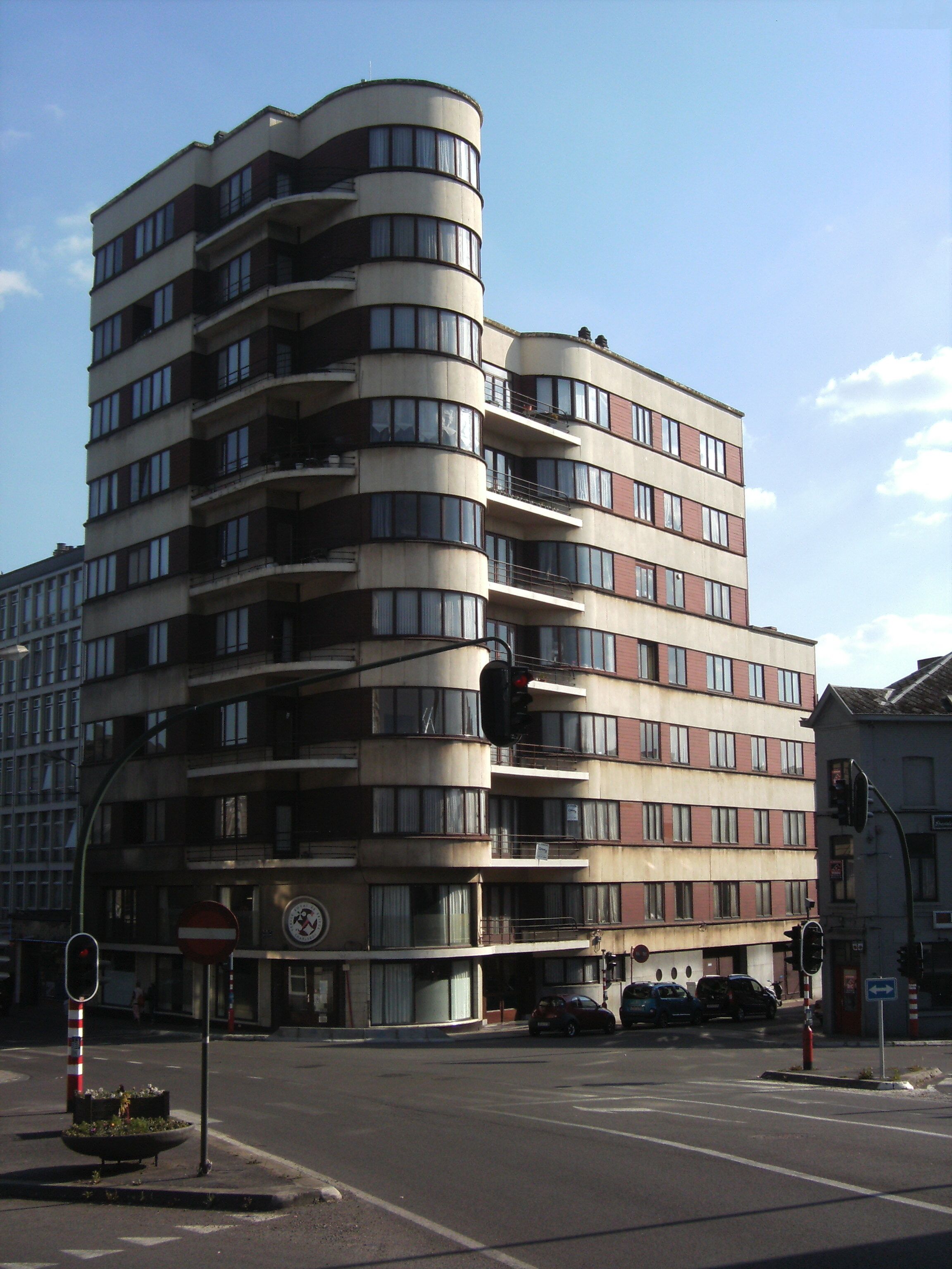 A multi-story building with balconies, a traffic light, and a no-entry sign.