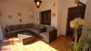 A living room with a sectional sofa, a coffee table, and a hanging light fixture. - SAONA VILLAS (VN FARNO): villa sleeps 6, private pool, wifi, air-conditioning (Les Tres Cales)