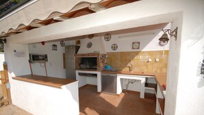 An outdoor kitchen with a microwave, grill, and sink. - SAONA VILLAS (VN FARNO): villa sleeps 6, private pool, wifi, air-conditioning (Les Tres Cales)