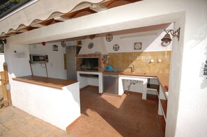 An outdoor kitchen with a microwave, grill, and sink. - SAONA VILLAS (VN FARNO): villa sleeps 6, private pool, wifi, air-conditioning (Les Tres Cales)