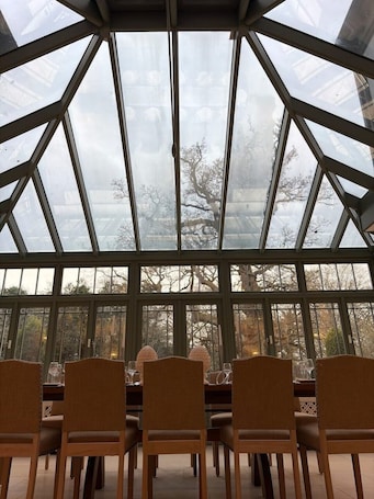 A dining area with a glass ceiling, wooden chairs, and a table set for four.