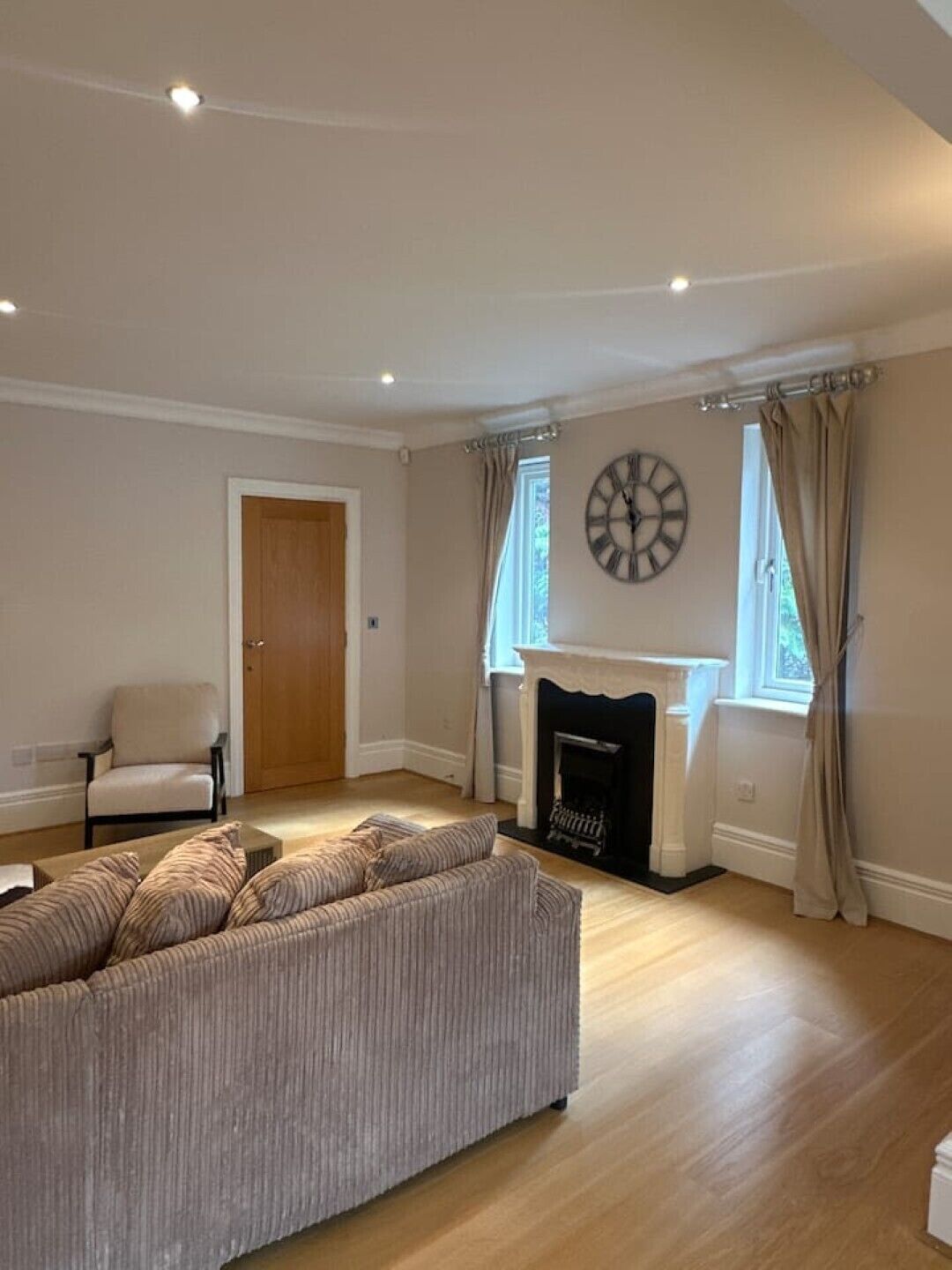 Un salon avec un canapé, une cheminée, une horloge et une porte.