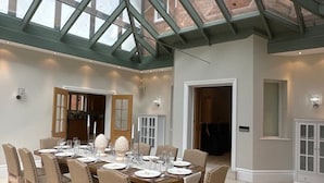 Un comedor con techo de cristal, una mesa grande dispuesta para seis personas y vistas al exterior.