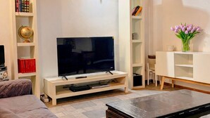 A living room with a TV, bookshelves, a coffee table, and a sofa. - Coconut House (Alzano Lombardo)