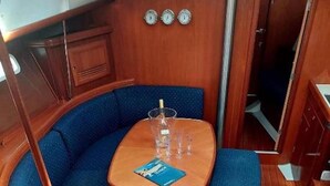 Un interior compacto y bien iluminado, con una zona de estar tapizada en azul, una pequeña mesa y suelo de madera.