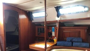 Una cabaña con interior de madera, un panel de control, una cama con ropa de cama azul y una ventana con cortinas.