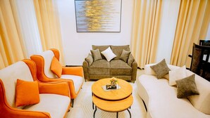 A living room with a sofa, armchairs, a coffee table, and curtains. - Juru House Rentals  (Kigali)