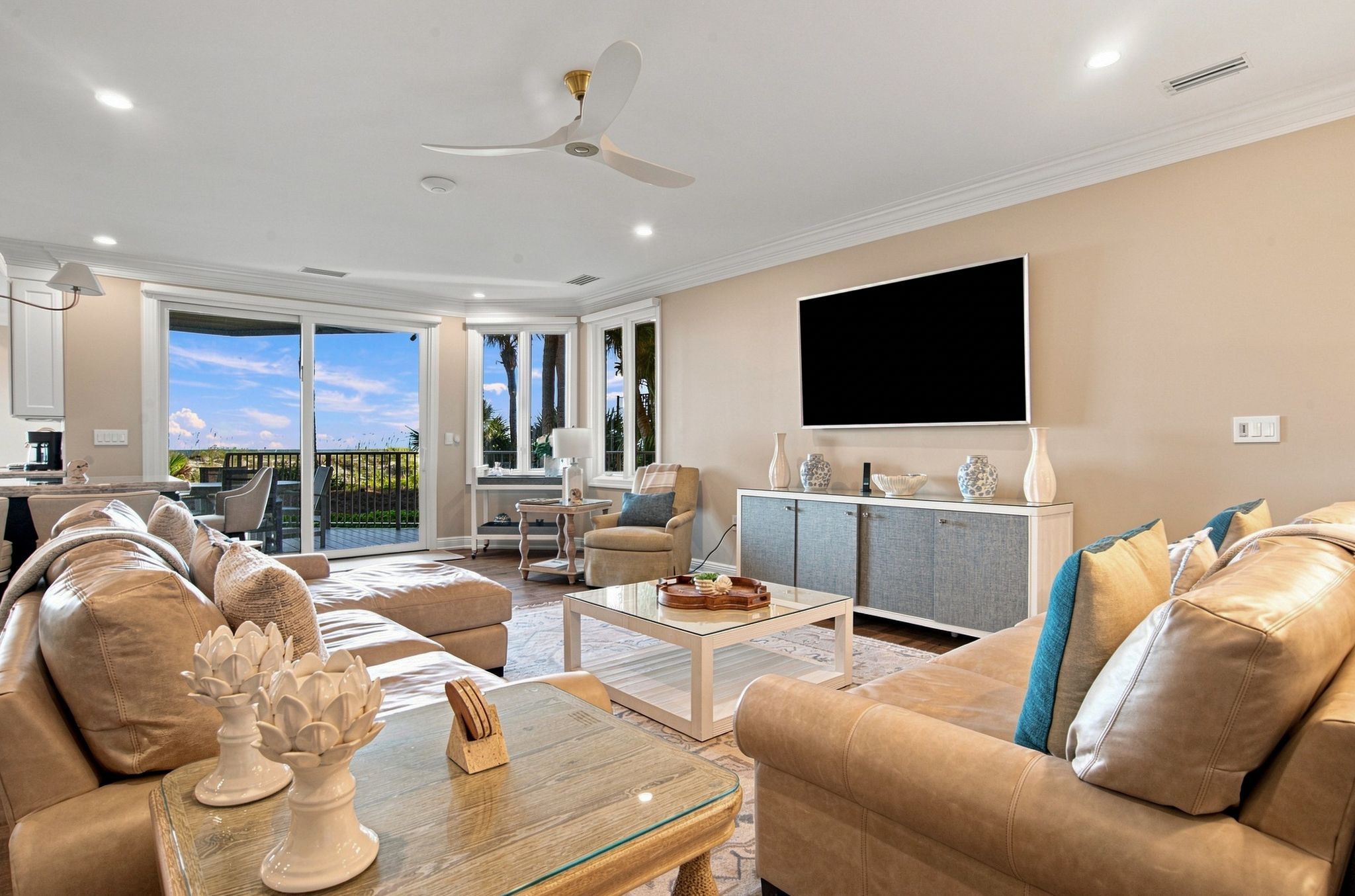 A spacious living room with a large sofa, a coffee table, and a television mounted on the wall.