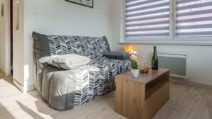 Ein modernes Wohnzimmer mit einer Couch, einem Holztisch und einem Fenster mit Jalousien.