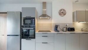 Eine moderne Küche mit Edelstahlgeräten, einer Mikrowelle, einem Backofen und einer Kaffeemaschine.
