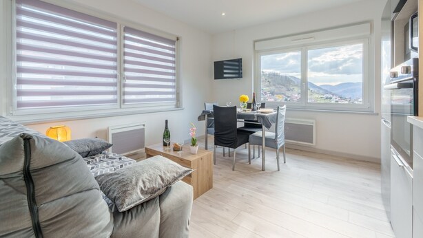 Eine moderne Wohnung mit Essbereich, Küche und großen Fenstern mit Blick auf die Stadt.