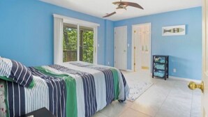Une chambre à coucher avec un lit, un ventilateur de plafond, une fenêtre et une porte.