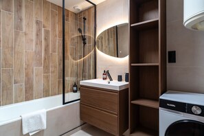 A modern bathroom with a wooden vanity, a built-in washing machine, and a large mirror. - Le Cocon Vannetais - 300m du Port de Vannes (Vannes)