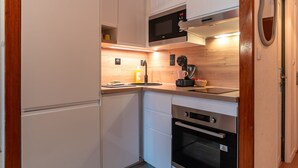 Eine kompakte Küche mit Mikrowelle, Backofen und Kaffeemaschine auf der Arbeitsfläche.