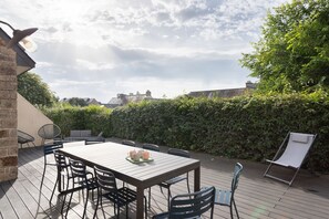 An outdoor patio with a table and chairs, a whiteboard, and a hedge in the background. - La Perle d'Arzon - Maison familiale en bord de mer (Arzon)