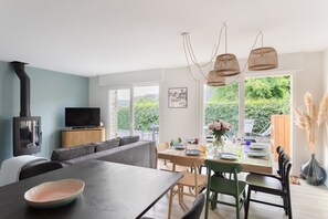 A modern living room with a sofa, dining table, and TV. - La Perle d'Arzon - Maison familiale en bord de mer (Arzon)