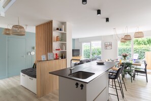 Una cocina moderna con una isla central, armarios de madera y una zona de comedor con sillas y mesa.