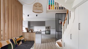 A modern kitchen with white cabinets, a wooden dining table, and a built-in oven. - La Perle d'Arzon - Maison familiale en bord de mer (Arzon)
