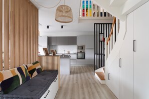 Una cocina moderna con armarios blancos, una mesa de comedor de madera y un horno empotrado.