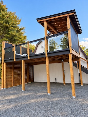 Un edificio moderno de dos pisos con una terraza de madera y un espacio al aire libre cubierto.
