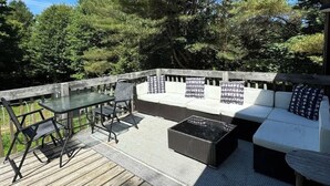 A deck with a glass-top table, black chairs, a sofa with patterned cushions, and a woven rug. - Private Barn Loft w/ King Bed | Cozy Forest Escape (Parry Sound)