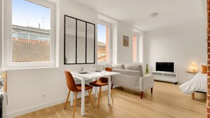 Uma sala de estar moderna com área de jantar, sofá, TV e lareira.