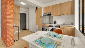 Uma cozinha moderna com armários de madeira, parede de destaque em tijolo e área de jantar com mesa posta para dois.