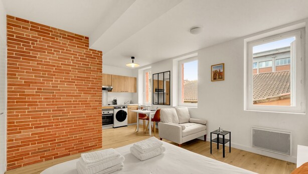 Um apartamento moderno com cozinha, sala de jantar e sala de estar com sofá e uma mesa pequena.
