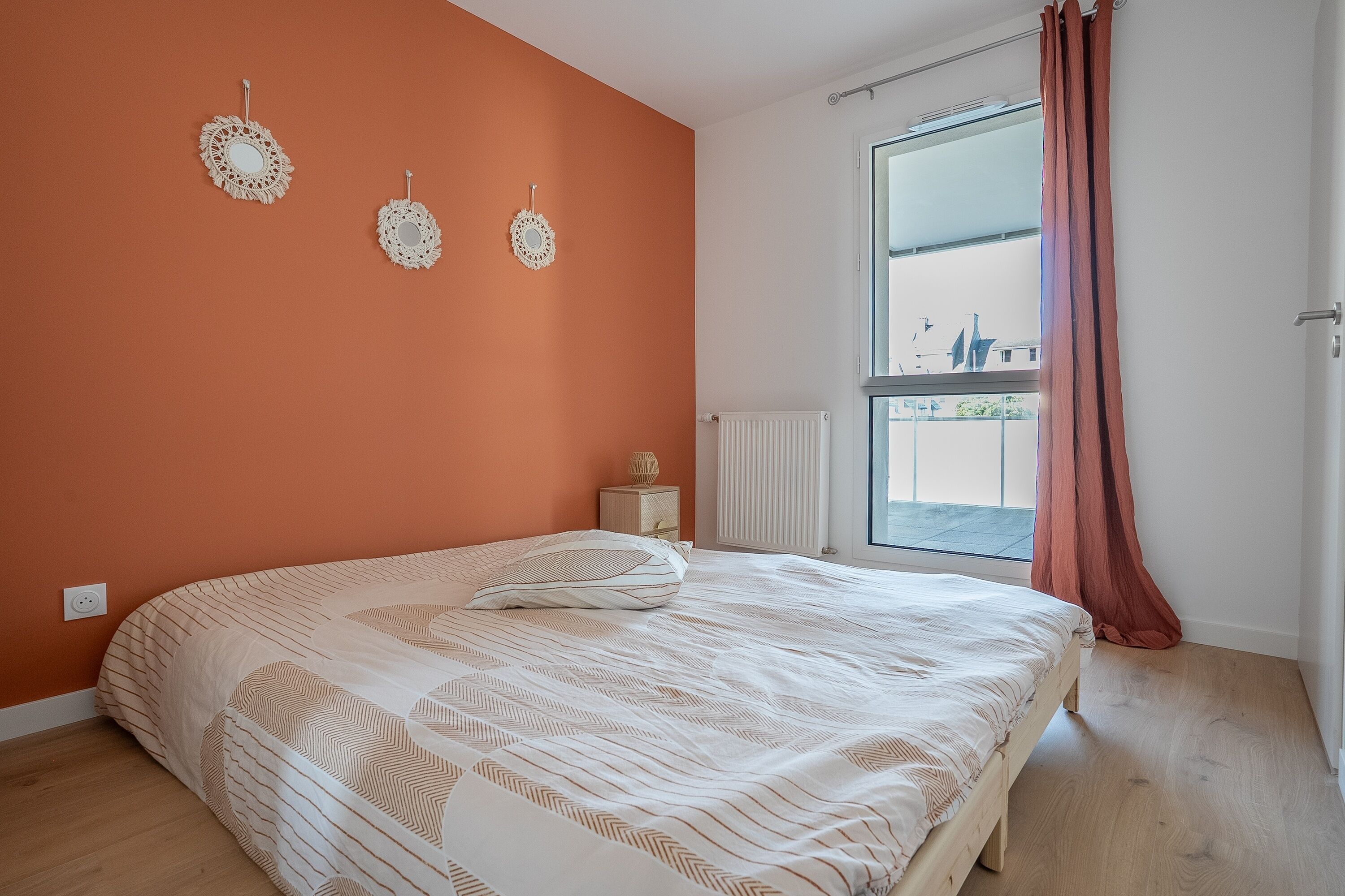 A bedroom with a large bed, a window with curtains, and a radiator.