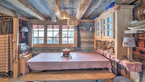 A rustic wooden interior with a checkered table, benches, and a window with a view. - Chalet de Mijoux - Proche remontées mécaniques (Mijoux)