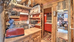 A rustic kitchen with wooden cabinets, a red appliance, and a red chair. - Chalet de Mijoux - Proche remontées mécaniques (Mijoux)