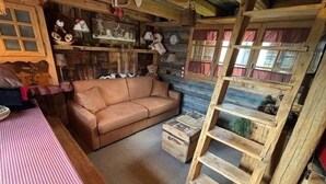 A rustic cabin interior with a wooden sofa, a table with a checkered tablecloth, and a wooden ladder. - Chalet de Mijoux - Proche remontées mécaniques (Mijoux)