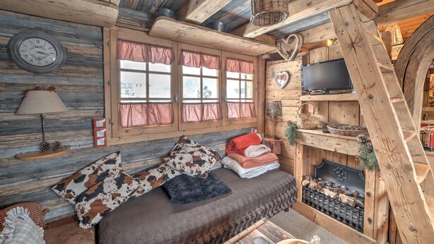 A rustic wooden room with a bed, a television, and a fireplace. - Chalet de Mijoux - Proche remontées mécaniques (Mijoux)
