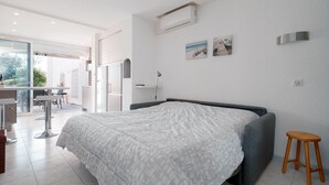 A modern bedroom with a bed, a small stool, and a desk area. - Le Nid d'Agde - Climatisé, à quelques pas du port (Agde)