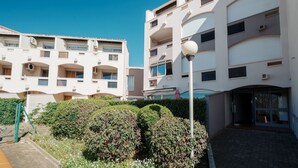 A multi-story residential building with balconies, a paved courtyard, and a street lamp. - Le Nid d'Agde - Climatisé, à quelques pas du port (Agde)