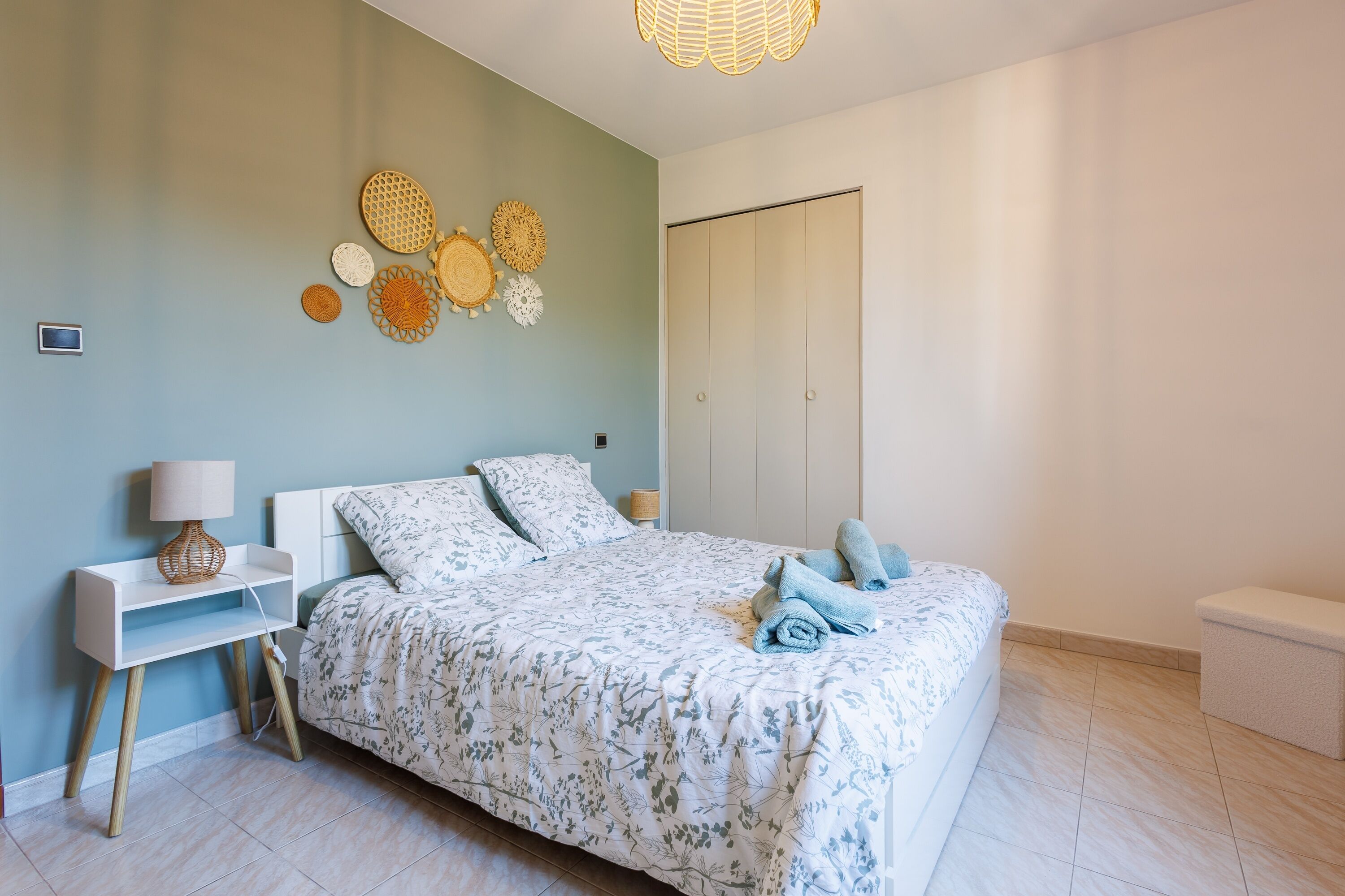 A bedroom with a bed, nightstands, a wardrobe, and wall decor.