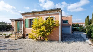 Una casa de dos pisos amb un camí de pedra, un petit porxo davanter i un arbre a la façana.