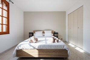 Un dormitorio con cama, mesitas de noche, armario y ventana.
